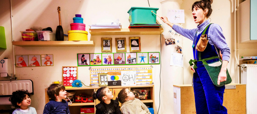 kinderen zitten op een bankje en kijken naar een vrouw die theater speelt